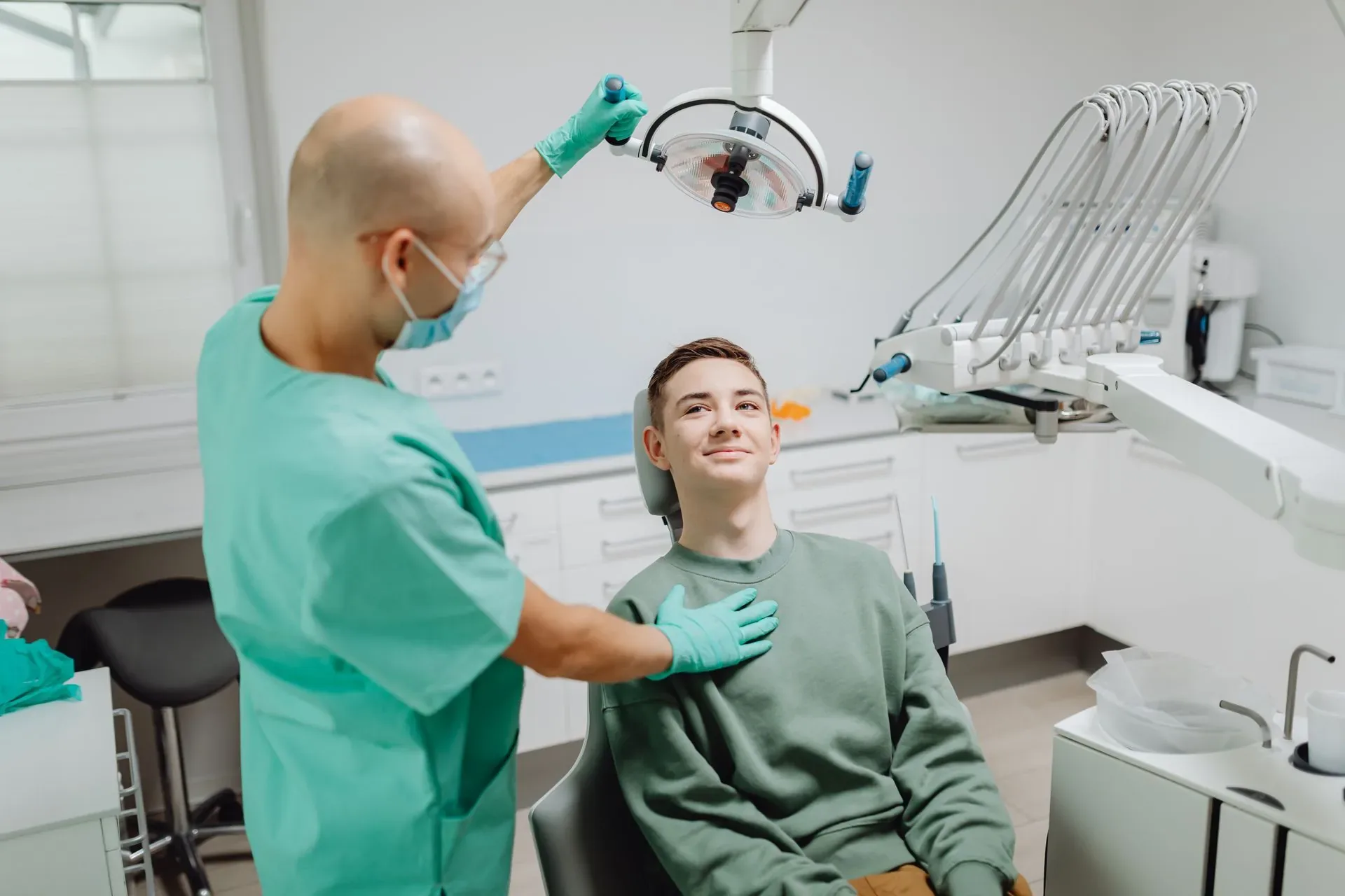 Klinikte diş hekimi ve gülümseyen genç hasta